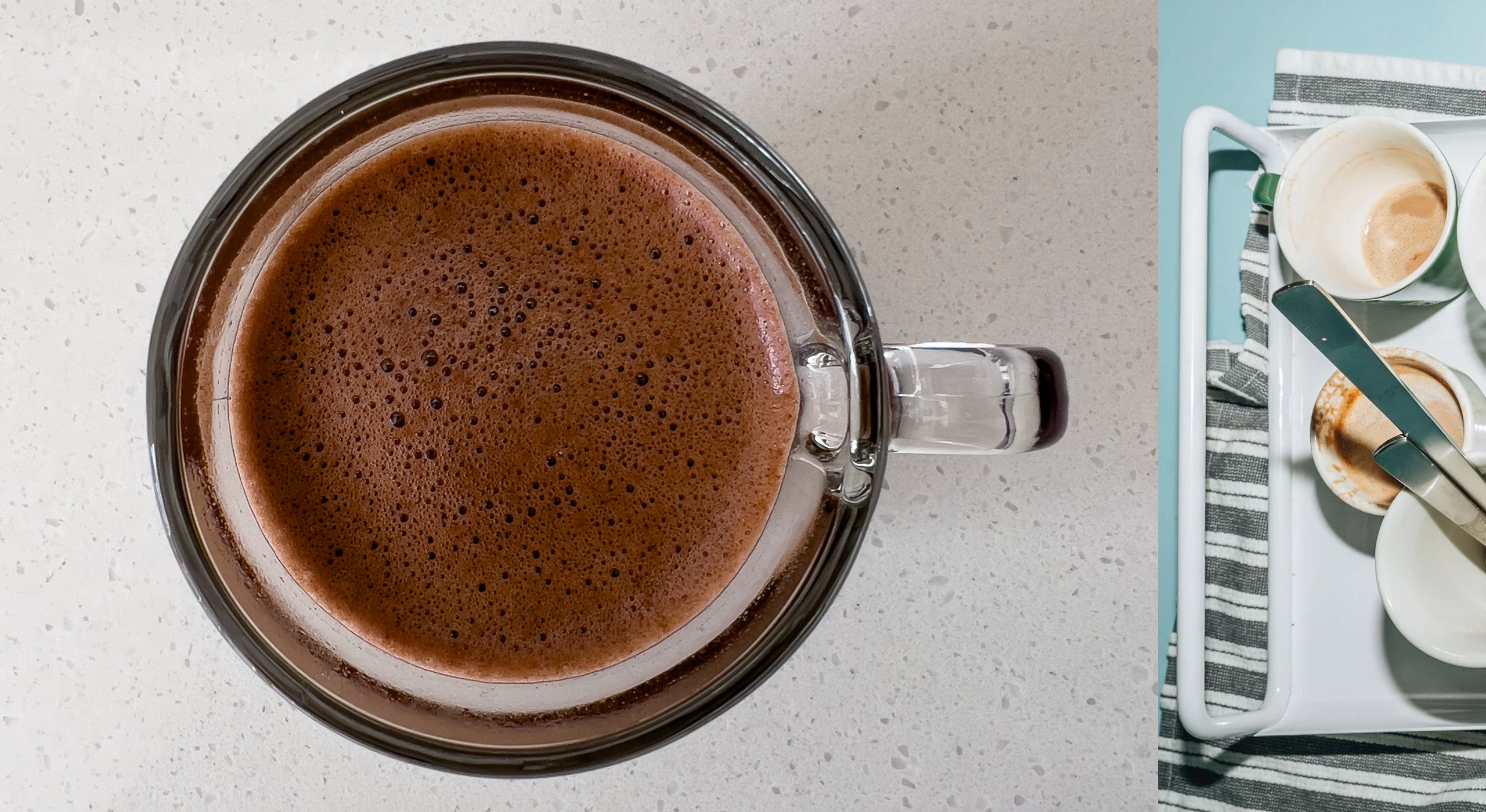 Glass mug filled with hot chocolate on a light surface, with a magazine in the background.