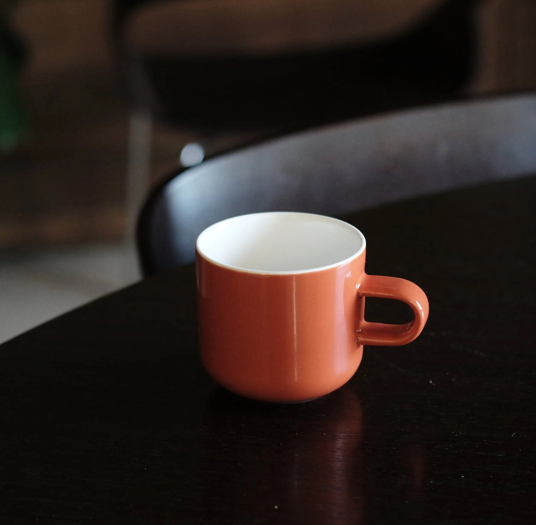 Orange mug on a dark surface with a blurred background