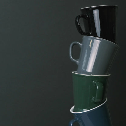 Stack of three mugs in black, gray, and green on a dark background